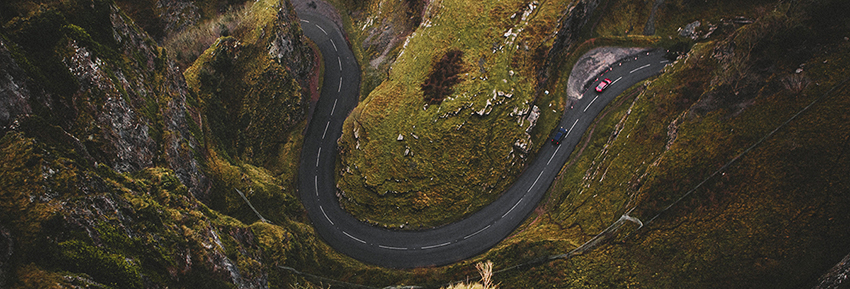 Zu sehen ist eine Alpenstraße aus der Vogelperspektive mit einem roten Auto